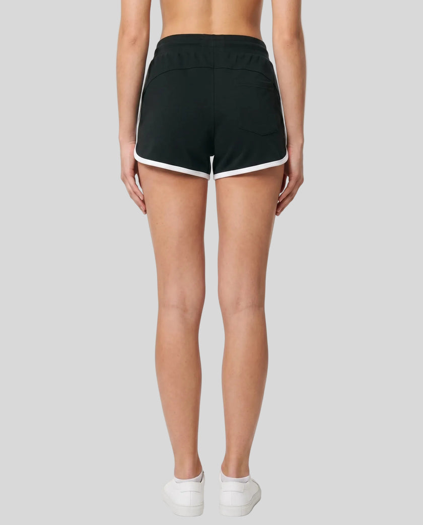 Back view of TrackLine Retro Shorts in Black with White contrast binding on model