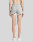 Back view of model wearing the Athlesi TrackLine Retro Shorts in flower gray and white