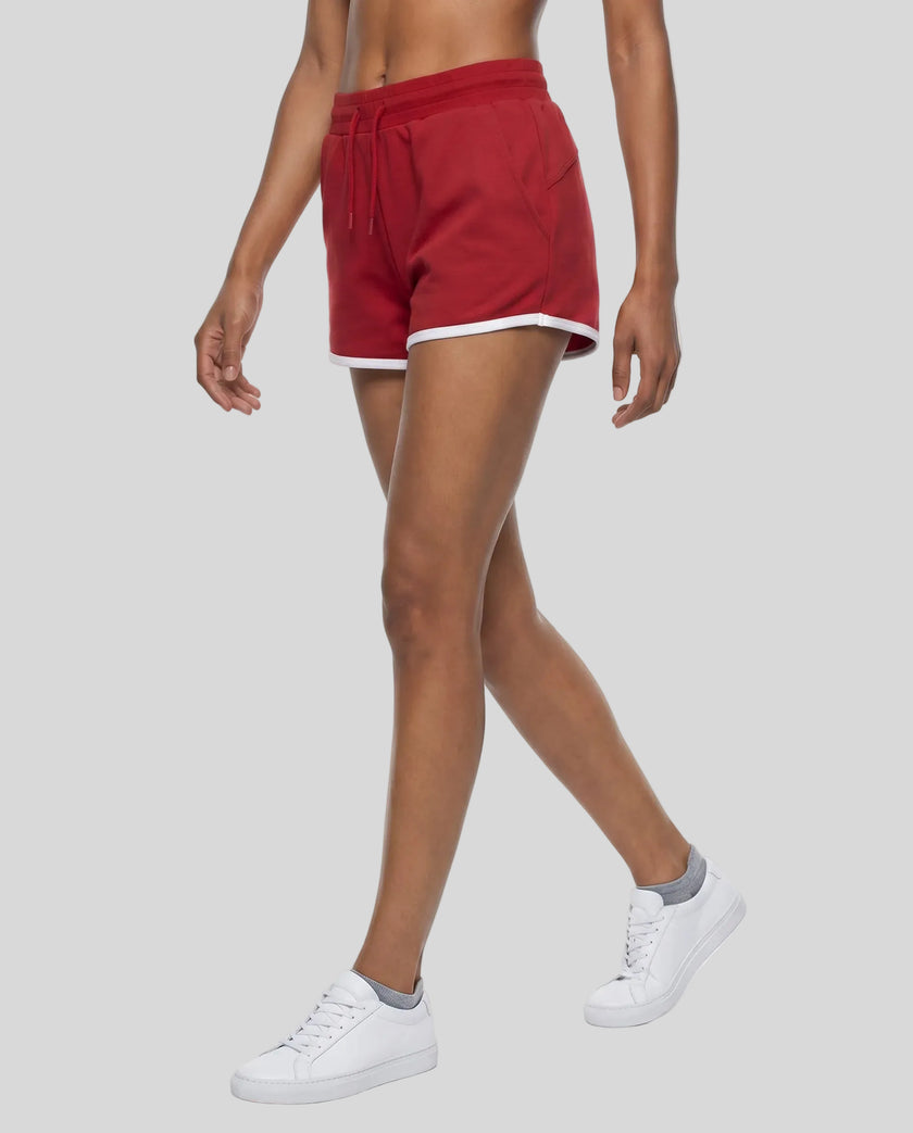 Side angled front view of model wearing the Athlesi TrackLine Retro Shorts in red and white