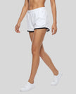Side angled front view of model wearing the Athlesi TrackLine Retro Shorts in white and black