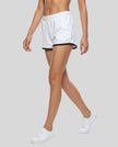 Model wearing TrackLine Retro Shorts in White with Black contrast binding side angle view