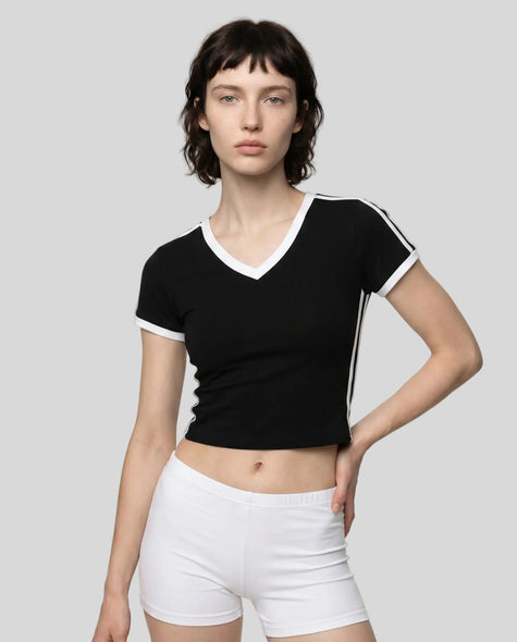 Mid body front view of a woman wearing the Athlesi TrackLine Retro V-Neck Tee in black