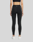 Rear view of a model wearing Trackline Riviera Leggings leg hem closeup in Black