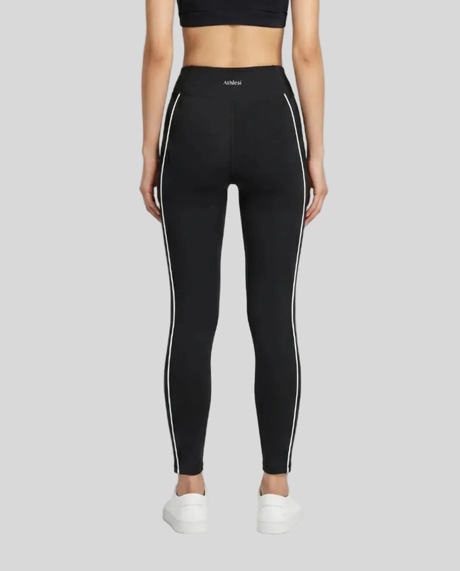 Rear view of a model wearing Trackline Riviera Leggings leg hem closeup in Black