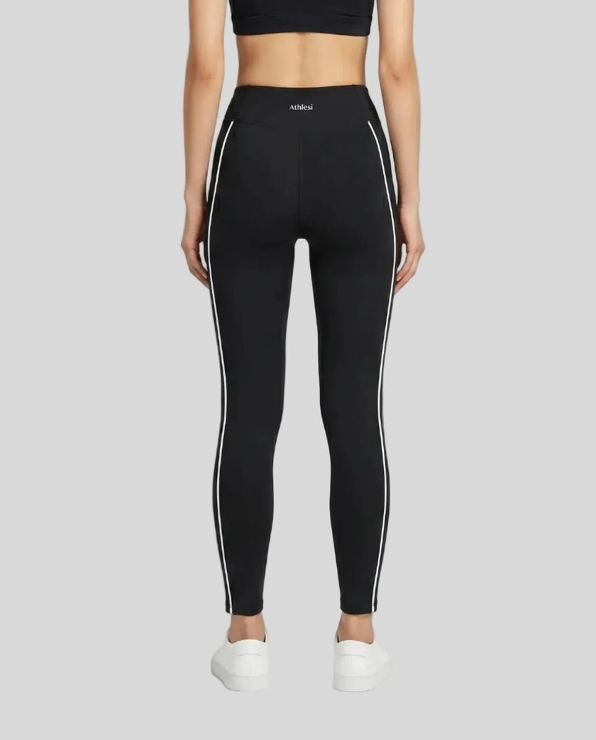 Rear view of a model wearing Trackline Riviera Leggings leg hem closeup in Black