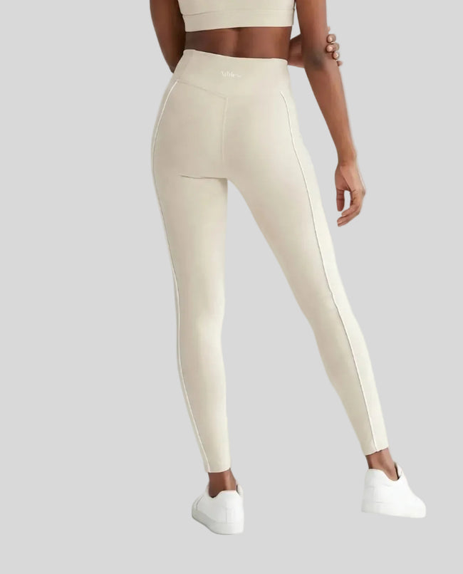 Rear view of a model wearing Trackline Riviera Leggings leg hem closeup in Light Apricot.