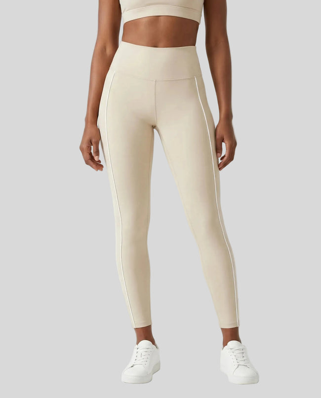 Front view of a model wearing Trackline Riviera Leggings leg hem closeup in Light Apricot.