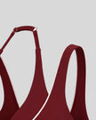 Close-up of Trackline Riviera Sports Bra in Wine Red, showing the wide shoulder straps and adjustable underband against a light gray background.
