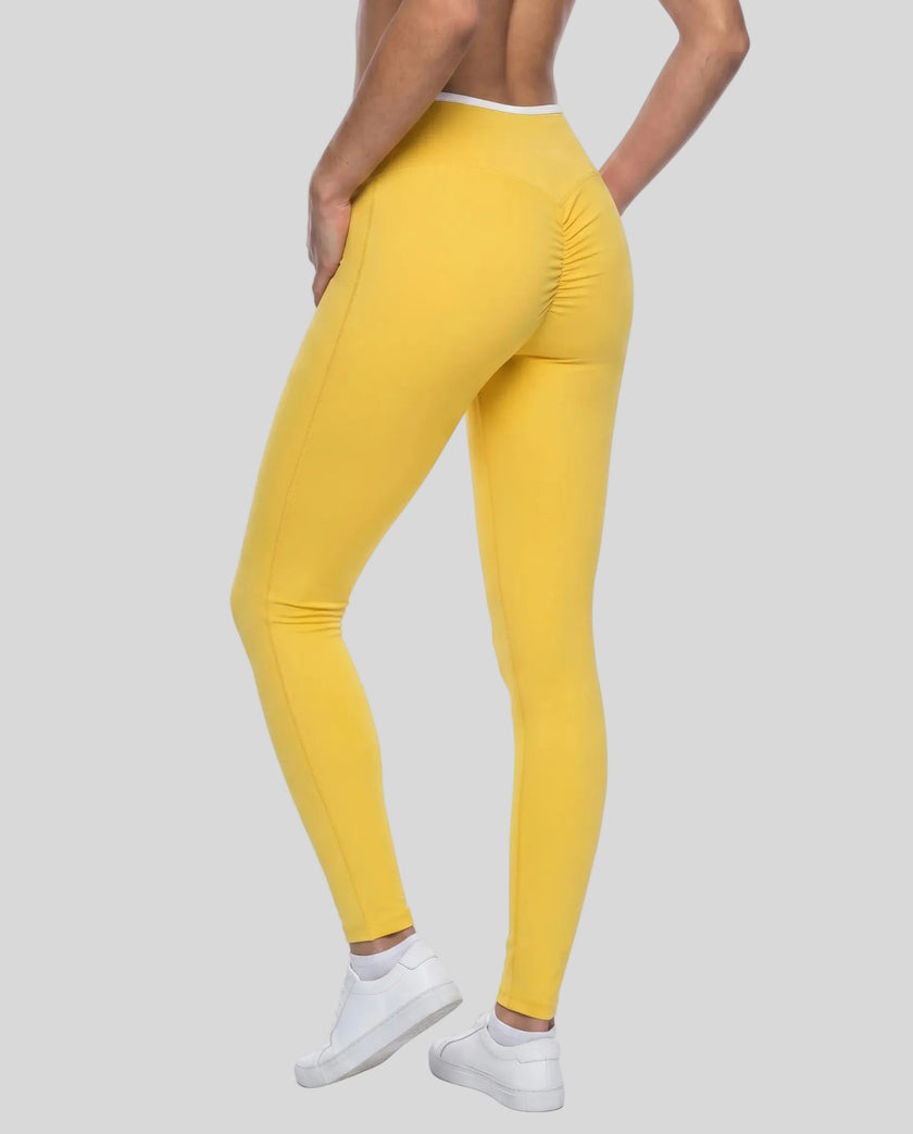 Back angled view of TrackLine Sculpt Leggings in yellow and white on model