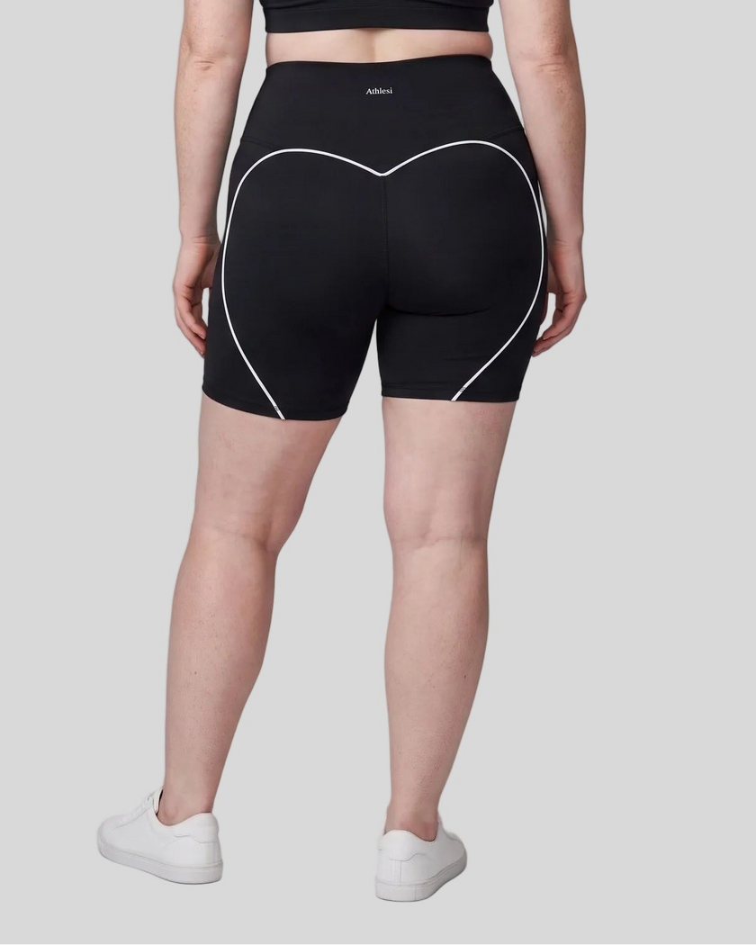 Lower body back view of woman wearing black TrackLine Sculpt Shorts with curved contrast piping