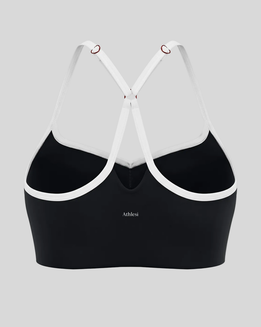 Back view of black TrackLine Sculpt Sports Bra featuring white crossover straps and open-back design