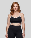 Upper body front view of woman wearing black TrackLine Sculpt Sports Bra with white contrast trim