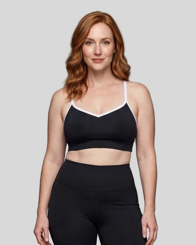 Upper body front view of woman wearing black TrackLine Sculpt Sports Bra with white contrast trim