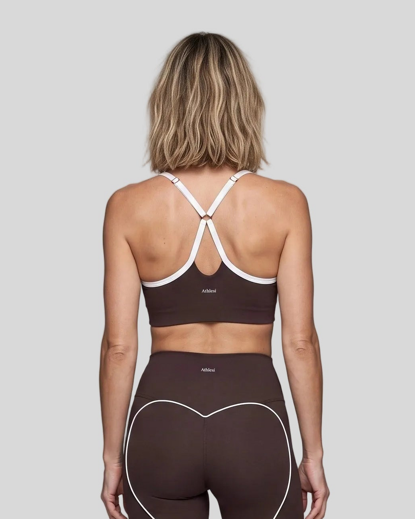 Upper body back view of woman wearing brown TrackLine Sculpt Sports Bra with white crossover straps