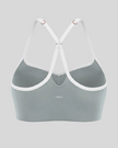 Back view of haze blue TrackLine Sculpt Sports Bra featuring white crossover straps and open-back design