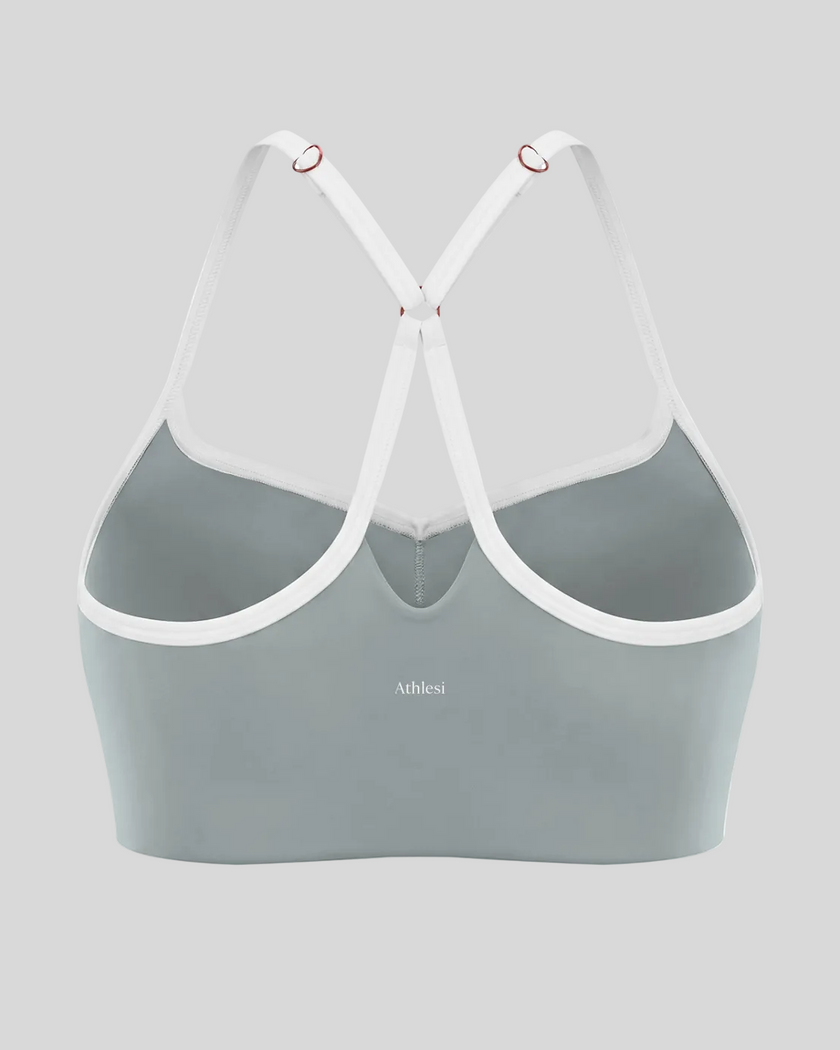 Back view of haze blue TrackLine Sculpt Sports Bra featuring white crossover straps and open-back design