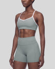 Angled front view of woman wearing haze blue TrackLine Sculpt Sports Bra with V-neckline
