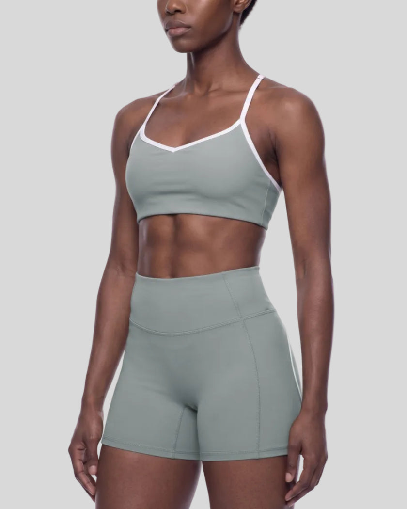 Angled front view of woman wearing haze blue TrackLine Sculpt Sports Bra with V-neckline