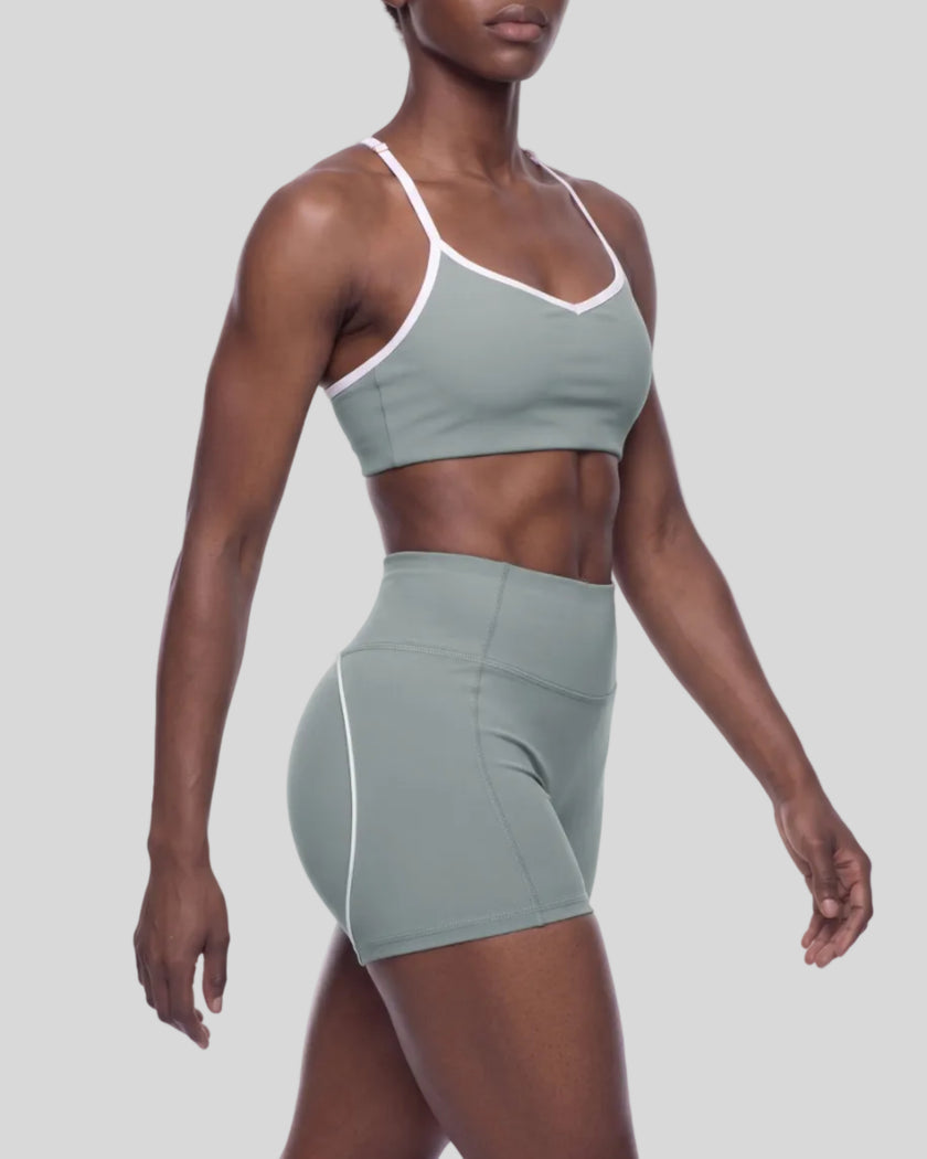 Angled side view highlighting the white crossover straps of haze blue TrackLine Sculpt Sports Bra