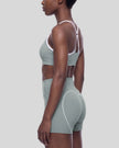 Mid body side view of woman wearing fitted haze blue TrackLine Sculpt Sports Bra