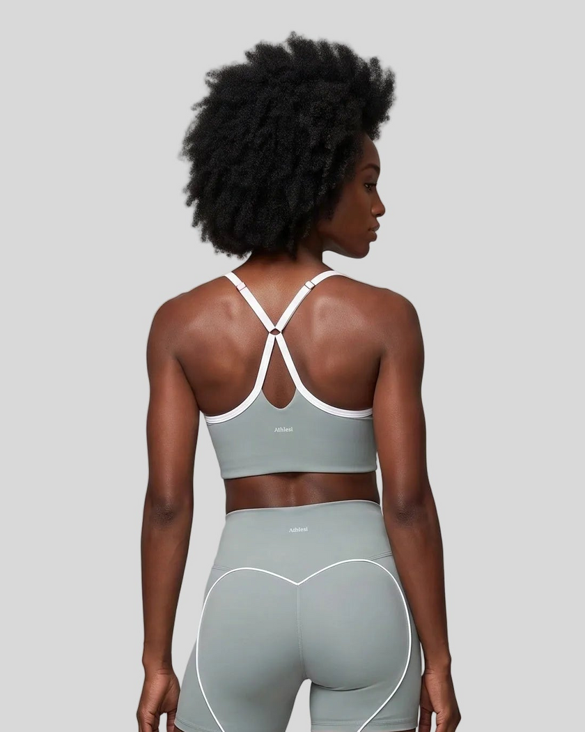 Upper body back view of woman wearing haze blue TrackLine Sculpt Sports Bra with white crossover straps