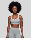 Upper body front view of woman wearing haze blue TrackLine Sculpt Sports Bra with white contrast trim