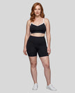 Full body front view of woman wearing black TrackLine Sculpt Sports Bra styled with matching activewear shorts
