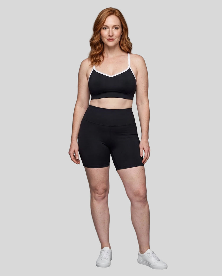 Full body front view of woman wearing black TrackLine Sculpt Sports Bra styled with matching activewear shorts