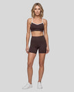Full body front view of woman wearing brown TrackLine Sculpt Sports Bra styled with matching activewear shorts