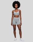 Full body front view of woman wearing haze blue TrackLine Sculpt Sports Bra styled with matching activewear shorts