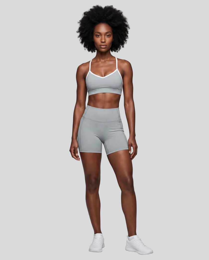 Full body front view of woman wearing haze blue TrackLine Sculpt Sports Bra styled with matching activewear shorts