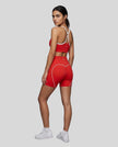 Full body angled back view of woman wearing red TrackLine Sculpt Sports Bra and matching TrackLine Sculpt Shorts