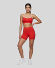 Full body front view of woman wearing red TrackLine Sculpt Sports Bra styled with matching activewear shorts
