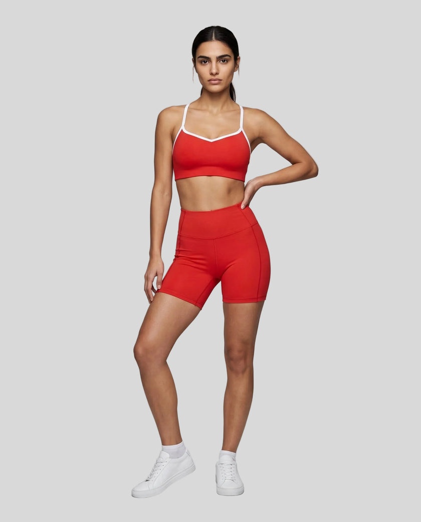 Full body front view of woman wearing red TrackLine Sculpt Sports Bra styled with matching activewear shorts