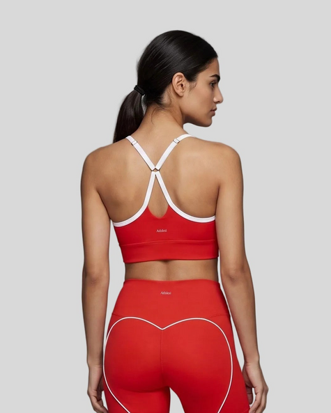 Upper body back view of woman wearing red TrackLine Sculpt Sports Bra with white crossover straps