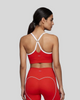 Upper body back view of woman wearing red TrackLine Sculpt Sports Bra with white crossover straps