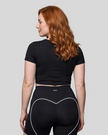 Upper body back view of woman wearing black TrackLine Sculpt Tee with subtle back logo