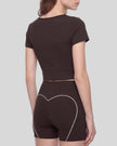 Angled back view of woman wearing brown TrackLine Sculpt Tee with cropped silhouette