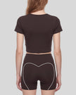 Mid body back view of woman wearing brown TrackLine Sculpt Tee with subtle back logo