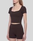 Angled front view of woman wearing brown TrackLine Sculpt Tee highlighting contour stitching