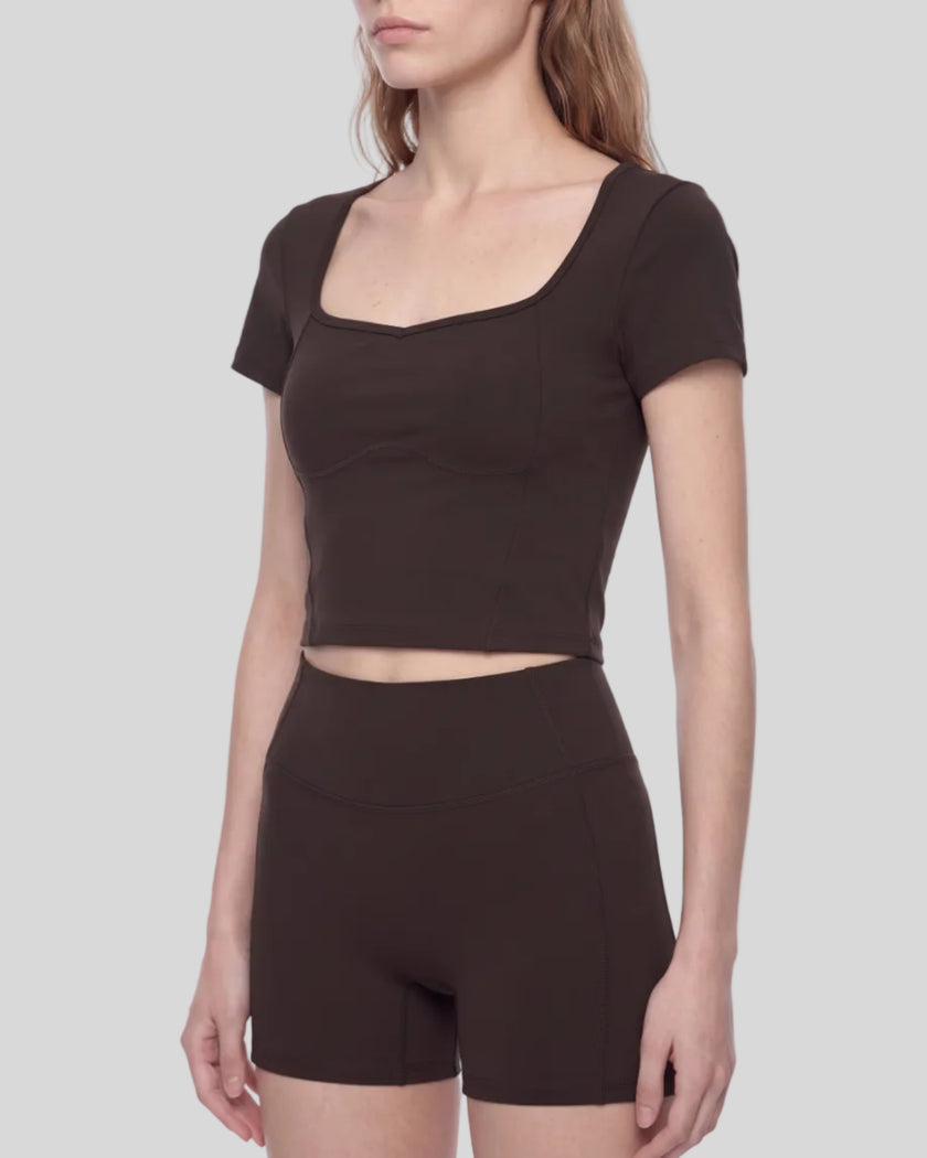 Angled front view of woman wearing brown TrackLine Sculpt Tee highlighting contour stitching