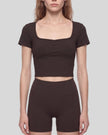 Mid body front view of woman wearing brown TrackLine Sculpt Tee with sculpted neckline