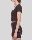 Mid body side view of woman wearing fitted brown TrackLine Sculpt Tee