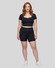 Full body front view of woman wearing black TrackLine Sculpt Tee styled with matching activewear shorts