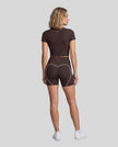 Full body back view of woman wearing brown TrackLine Sculpt Tee with coordinating activewear shorts
