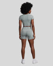 Full body back view of woman wearing haze blue TrackLine Sculpt Tee with coordinating activewear shorts