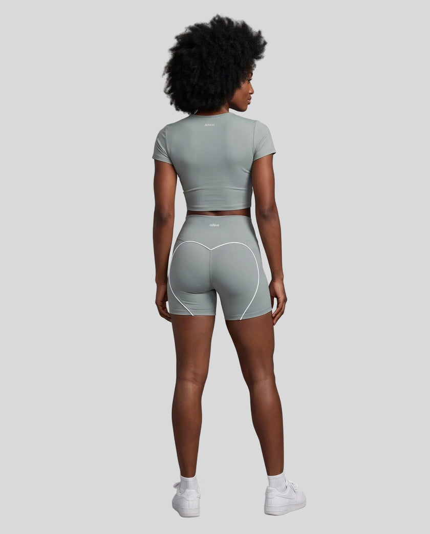 Full body back view of woman wearing haze blue TrackLine Sculpt Tee with coordinating activewear shorts