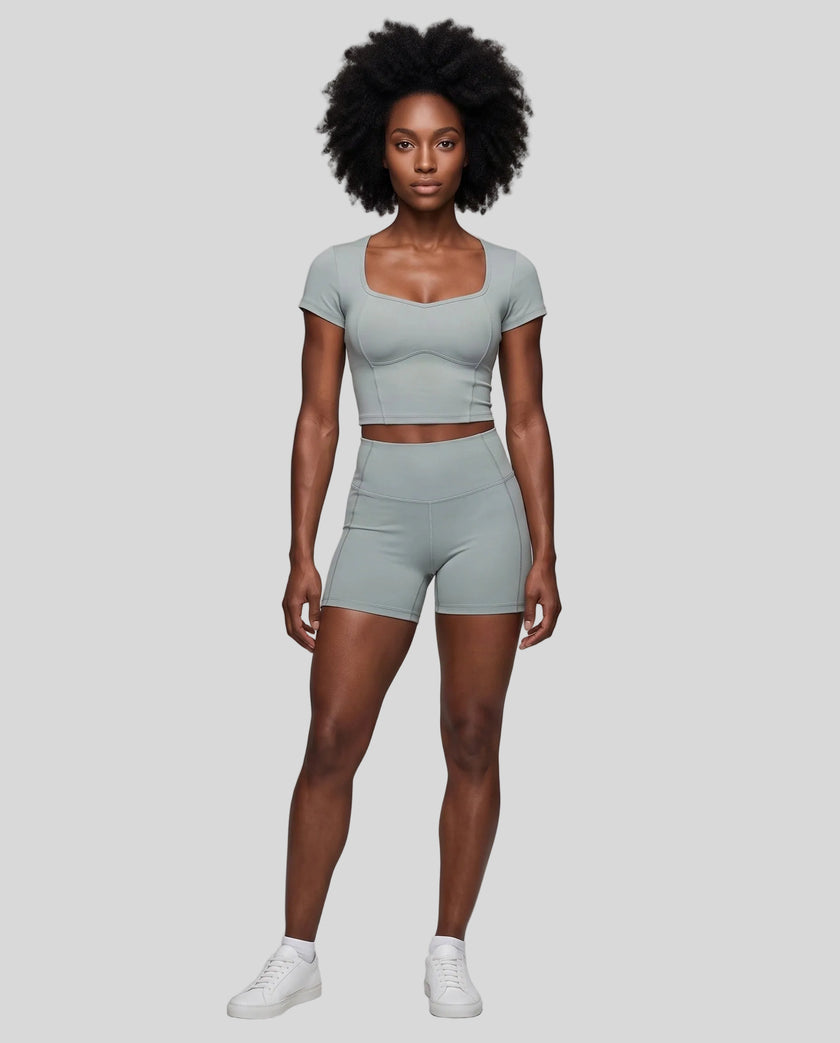 Full body front view of woman wearing haze blue TrackLine Sculpt Tee styled with matching activewear shorts