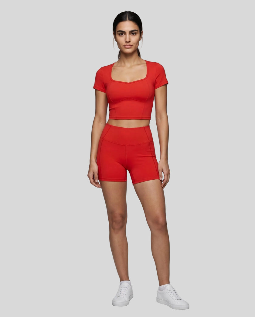 Full body front view of woman wearing red TrackLine Sculpt Tee styled with matching activewear shorts