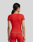 Upper body back view of woman wearing red TrackLine Sculpt Tee with subtle back logo